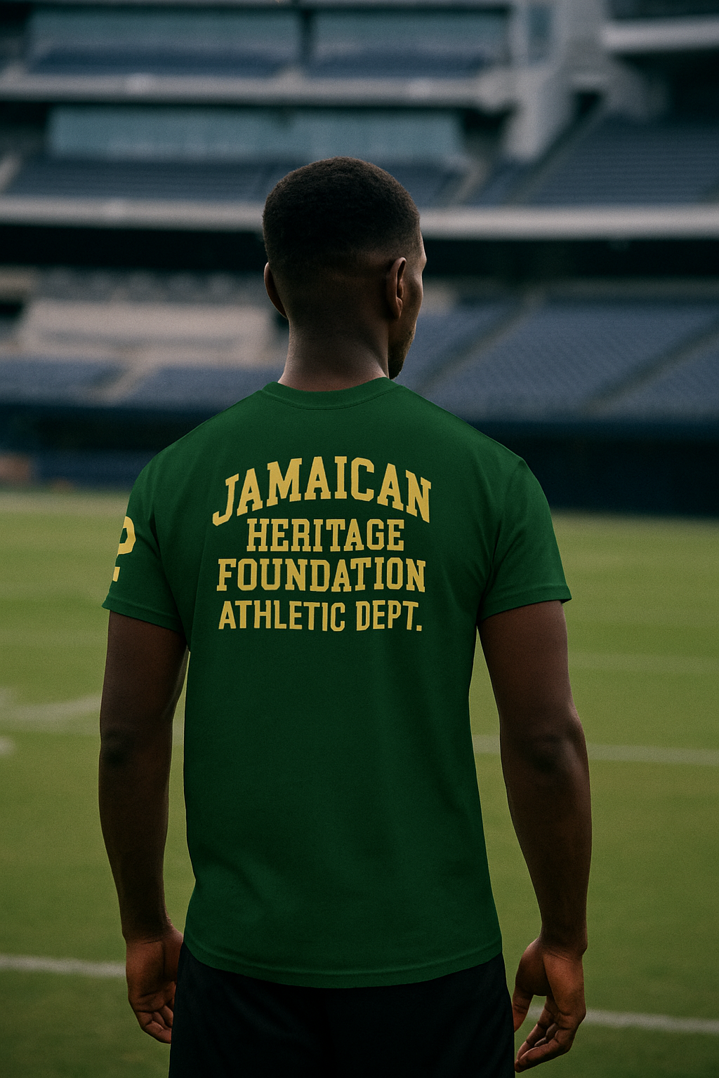 Person wearing a green t-shirt with 'Jamaican Heritage Foundation Athletic Dept.' text on a sports field.
