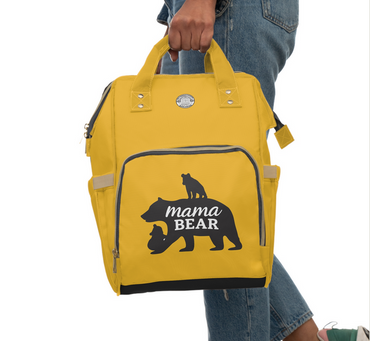 Yellow backpack with 'mama bear' design held by a person wearing jeans.