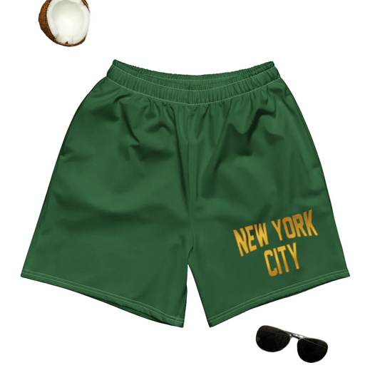 Green shorts with 'New York City' text on a gray surface with palm leaves and sandals.