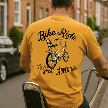 Person wearing a yellow t-shirt with a bicycle graphic and text on the back, standing outdoors.