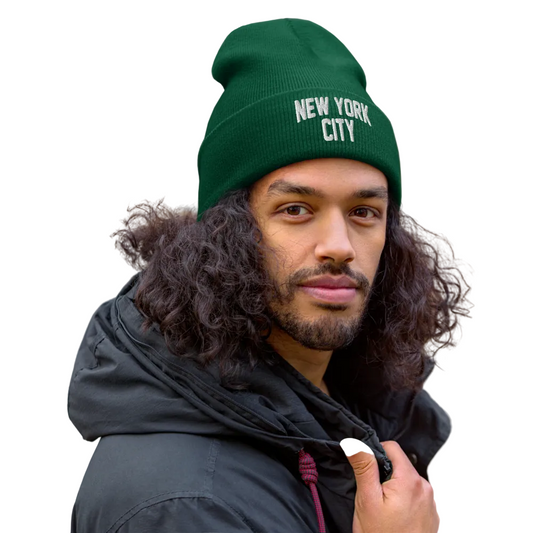 Man wearing a green 'New York City' beanie with a blurred natural background