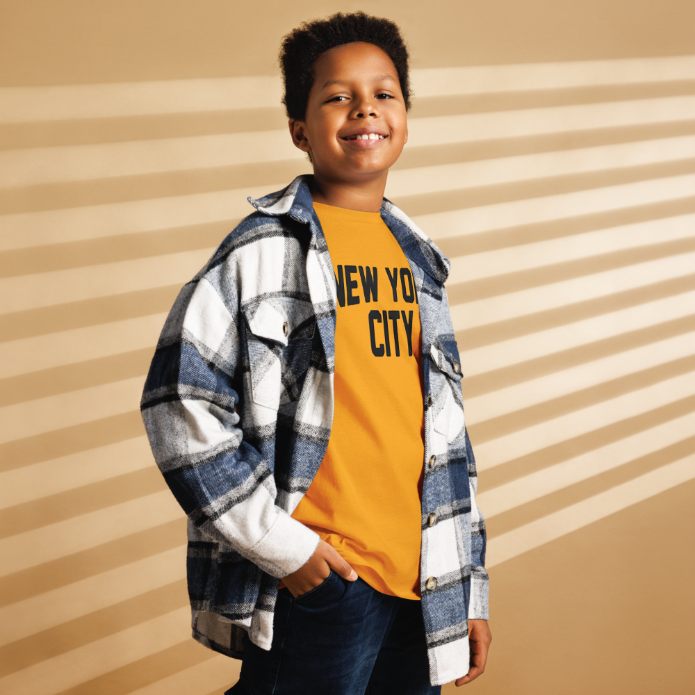 Child wearing a plaid shirt over a 'New York City' t-shirt against a striped background