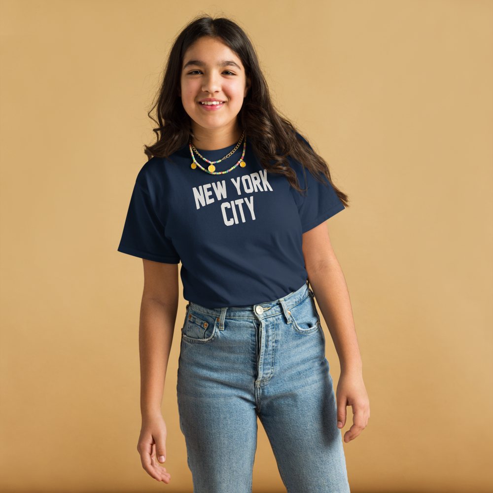 Person wearing a navy blue t-shirt with 'New York City' text on a beige background