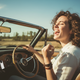 Person singing along to music while driving with a USB drive plugged into the car dashboard