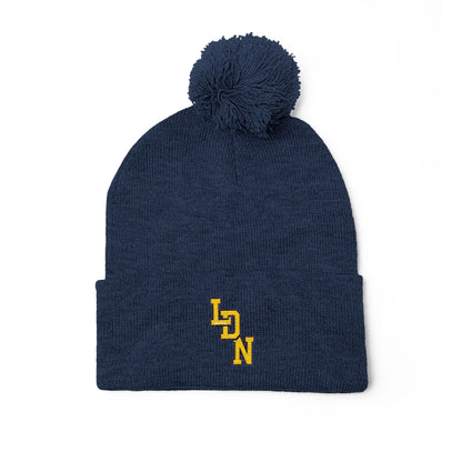 Navy blue beanie with pom-pom and yellow logo on a white background