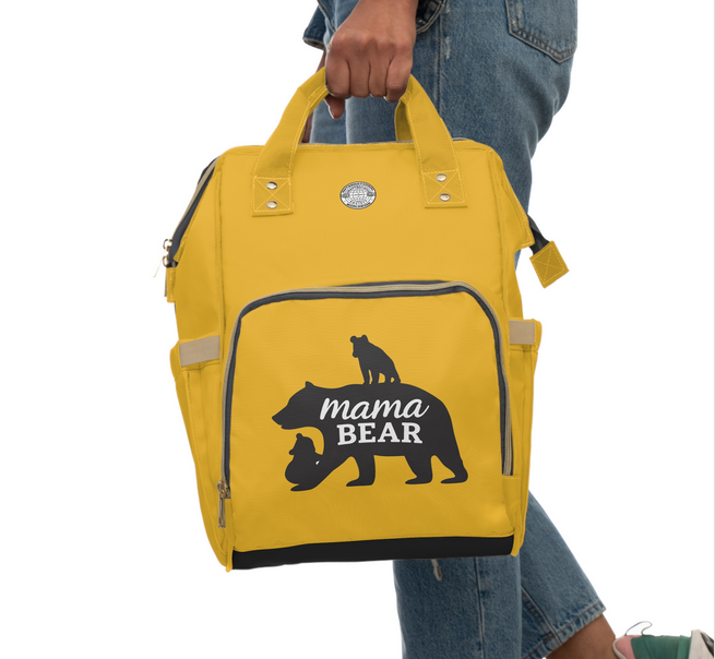 Yellow backpack with 'mama bear' design held by a person wearing jeans.
