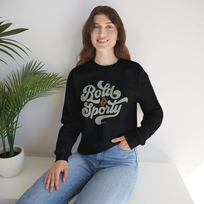 Woman wearing a black sweatshirt with 'Bold & Sporty' text, sitting on a white surface with a plant in the background.