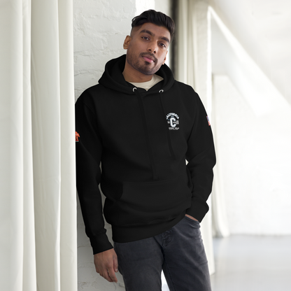 Man wearing a black hoodie with a logo, standing against a white wall.