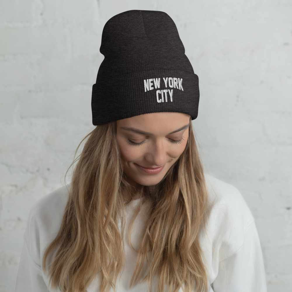 Woman wearing a black beanie with 'New York City' text against a light gray background