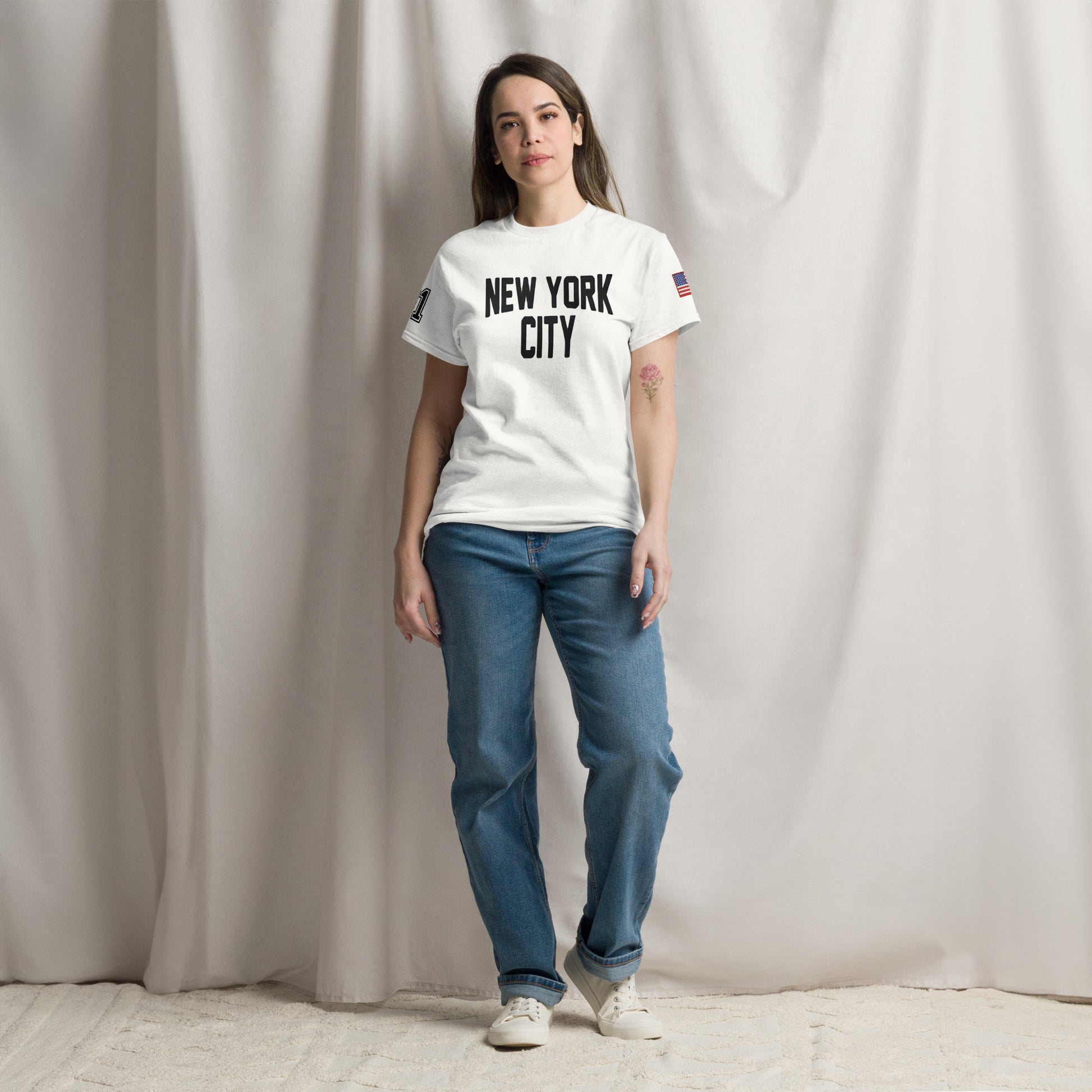 Person wearing a white 'New York City' t-shirt and blue jeans against a plain background