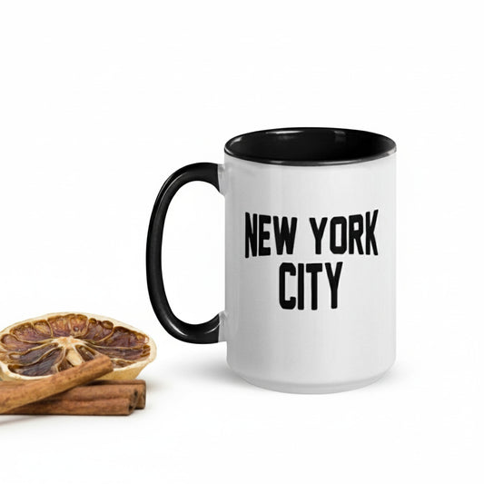White mug with black handle and 'New York City' text, placed on a surface with decorative elements.