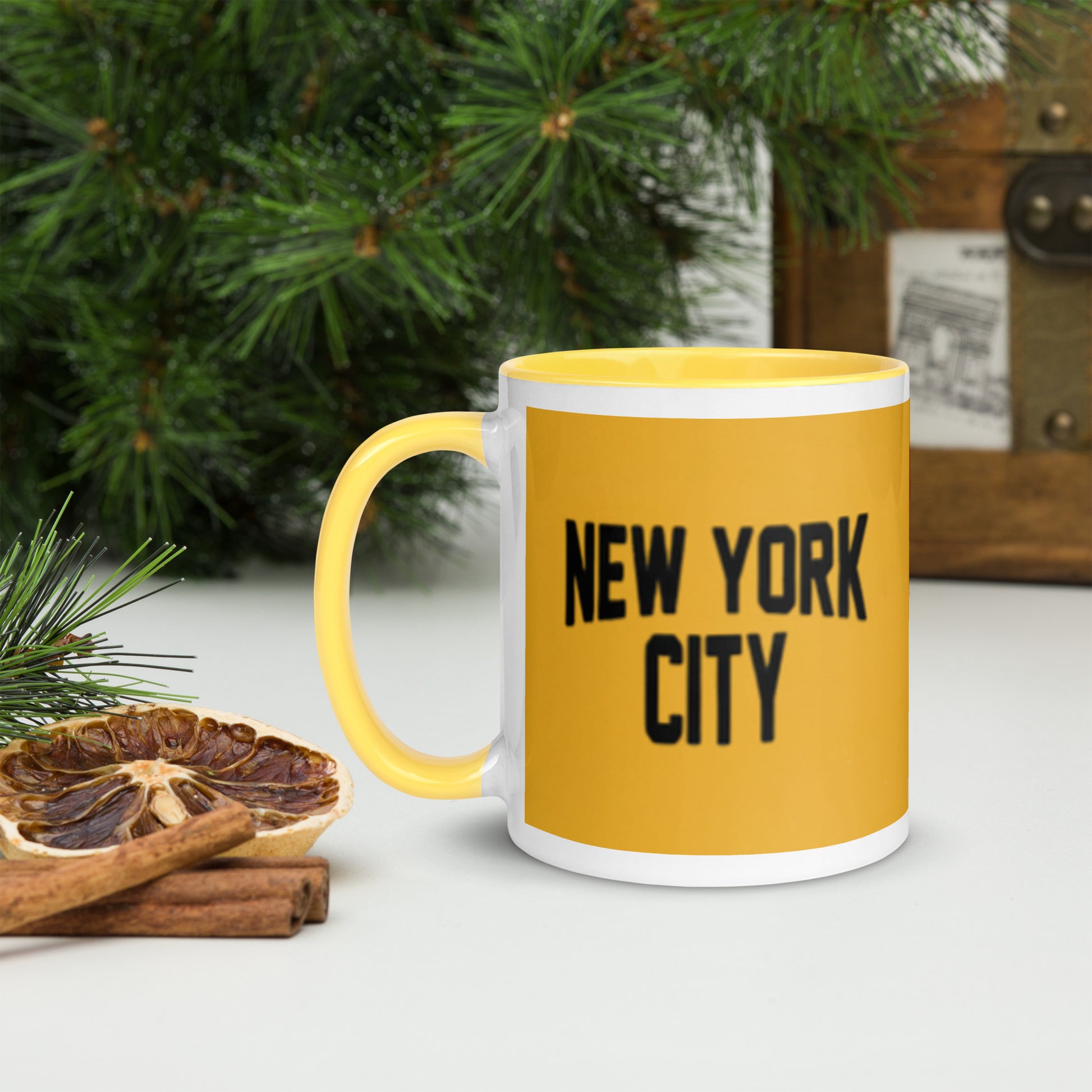 Yellow mug with 'New York City' text on a white surface with Christmas decorations.