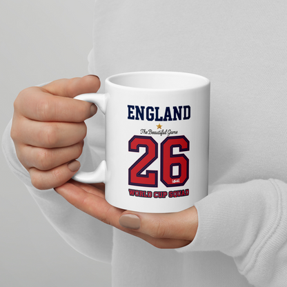 White mug with 'England' and number '26' printed on it, held by a person against a light gray background.